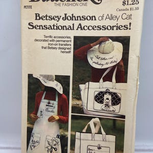 Può includere: Modello di cucito vintage Butterick con accessori Betsey Johnson of Alley Cat. La copertina mostra un grembiule bianco, borse e un cappello, tutti con disegni a tratto nero e testo. Il numero del modello è 3850.