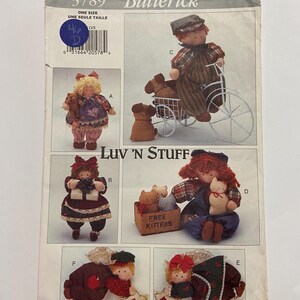 May include: A vintage Butterick sewing pattern with doll designs. The pattern shows dolls with accessories, including a bicycle, kittens, and stars. The text "Luv 'N Stuff" and "Free Kittens" are visible on the pattern.