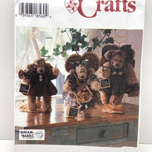 May include: Simplicity Crafts sewing pattern featuring teddy bear dolls. The pattern includes instructions for creating several teddy bears with various outfits and accessories. The bears are displayed on a wooden surface, showcasing the finished product.