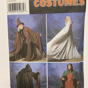 May include: Simplicity Costumes pattern featuring four costume designs: a wizard, a hooded figure, a medieval woman, and a monk. The pattern includes sizes XS to XL. The packaging is primarily white, black, and orange.