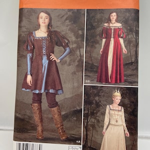 Könnte beinhalten: Simplicity Schnittmuster 1773 R5 mit mittelalterlichen Kleidern. Das Schnittmuster enthält die Größen 14, 16, 18, 20 und 22. Das Cover zeigt drei verschiedene Kleiderdesigns in Braun-, Rot- und Beigetönen. Das Schnittmuster enthält den Text "Simplicity".