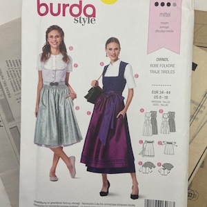 May include: A Burda Style sewing pattern envelope, number 6268, for a dirndl dress. The cover displays two variations of the dress, one in light blue and one in dark blue with a purple apron, including size range US 8-18 and technical sketches.