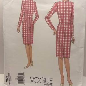 May include: A Vogue Patterns sewing pattern envelope for a knee-length dress with a red and white gingham check print, long sleeves, a high neckline with a ruffled collar, and a button-down front. The envelope displays the number 1004 and size 22.