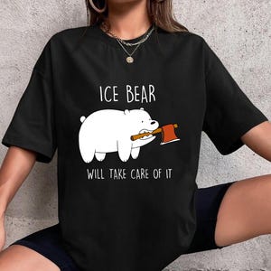 May include: Black t-shirt featuring a cartoon Ice Bear character holding a small axe. The text "ICE BEAR" is above the bear, and "WILL TAKE CARE OF IT" is below. The design is in white and red.