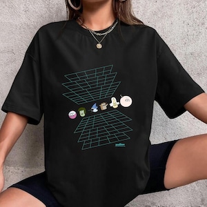 May include: Black t-shirt featuring a graphic of cartoon characters and a geometric design in teal. The design includes several characters in a grid-like pattern. The shirt is a casual, oversized style.