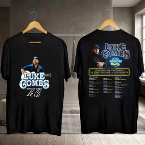 May include: Black t-shirts featuring a graphic of Luke Combs playing a guitar, with the text "LUKE COMBS WORLD TOUR." The back of the shirt has a tour graphic with the text "Saturday Nights."
