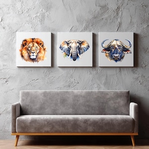 Puede incluir: Conjunto de tres impresiones en lienzo cuadradas con retratos de acuarela de fauna africana. La obra de arte incluye un león con tonos naranja y amarillo, un elefante con tonos azules y grises, y un búfalo con tonos marrones y azules.