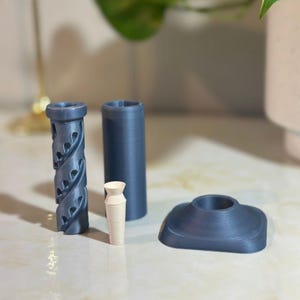 May include: Four 3D printed objects: a blue vase with a spiral design, a blue cylinder, a white cylinder, and a blue circular base.