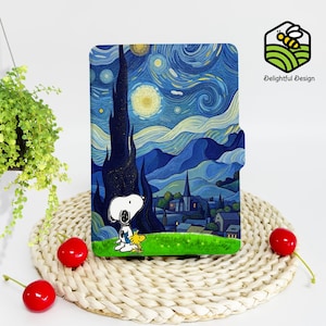 May include: A blue and yellow illustrated case for an e-reader featuring a starry night sky with a town in the distance and a cartoon dog and bird in the foreground. The text "Delightful Design" is in the upper right corner of the image.