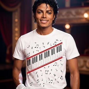 Pode incluir: Uma camiseta branca com um desenho de teclado de piano, listras vermelhas e notas musicais. A camiseta é usada por uma pessoa usando uma luva com lantejoulas.