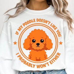 Könnte beinhalten: Weißes Sweatshirt mit einem kreisförmigen Grafikdesign, das eine orangefarbene Pudel-Illustration zeigt. Der Text um den Pudel lautet: „WENN MEIN POODLE DICH NICHT MAG, WERDE ICH ES WAHRSCHEINLICH AUCH NICHT.“