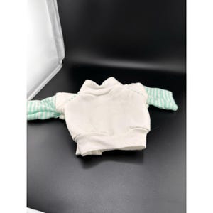 May include: A white sweatshirt with mint green and white striped sleeves. The sweatshirt has a high neckline and ribbed cuffs. The garment is made of a soft, comfortable material.