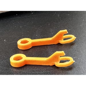 Könnte beinhalten: Zwei orangefarbene Kunststoffteile mit einer Schlaufe an einem Ende und einem Haken am anderen Ende.