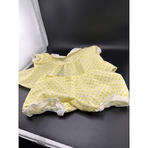 Può includere: Un completo giallo a pois, composto da un top e pantaloncini. Il completo ha finiture in pizzo bianco ed è realizzato in un tessuto leggero. Il top ha maniche corte e scollo tondo. I pantaloncini hanno un elastico in vita.