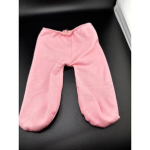 May include: A pair of light pink baby pants. The pants are made of a soft material and have a gathered elastic waistband. The legs taper to a gathered cuff at the ankles. The pants are designed for a baby or toddler.
