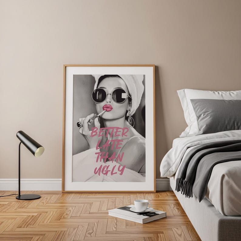 Pu&ograve; includere: Stampa in bianco e nero incorniciata con una donna che applica il rossetto, indossa occhiali da sole e un asciugamano. La stampa ha il testo "Better Late Than Ugly" in rosa. La stampa &egrave; in una stanza con un letto e una lampada nera.