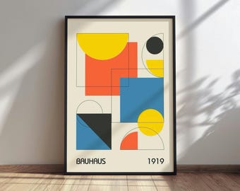 May include: A framed vertical poster featuring geometric shapes in yellow, orange, blue, and black on a cream background. The composition includes circles, squares, and rectangles with thin black outlines. The text BAUHAUS and 1919 appear at the bottom.