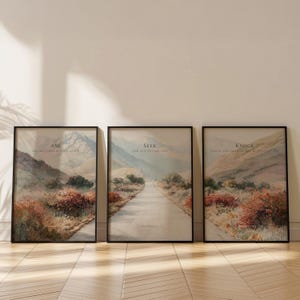 May include: Three framed landscape art prints with black frames. Each print features a scenic view of a road winding through a mountain landscape. The prints have text that reads "Ask", "Seek", and "Knock".