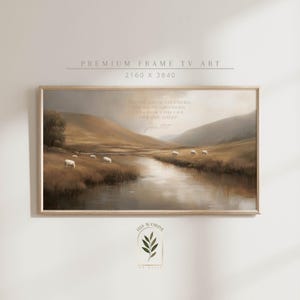 Puede incluir: Una impresión artística enmarcada que presenta una serena escena pastoral con un río, colinas y ovejas. La obra de arte tiene una cálida paleta de colores marrones y beiges. El texto en la parte superior dice "Premium Frame TV Art". La impresión incluye el texto "I AM THE GOOD SHEPHERD..." y "John 10:11".