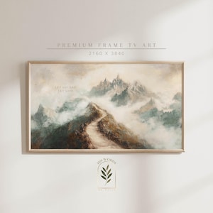 Puede incluir: Una pintura enmarcada que representa una cordillera con un camino sinuoso que lleva a la cima. El cielo es de un azul suave y apagado, y las montañas están cubiertas de una ligera niebla. El texto "Let go and let God" está escrito en blanco en la pintura.