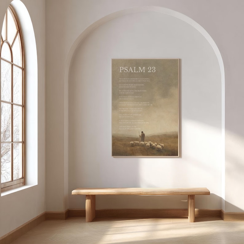 May include: A framed print with the text "PSALM 23" at the top. The artwork depicts a shepherd with a flock of sheep in a field, with a muted color palette. The print is displayed on a white wall above a wooden bench.