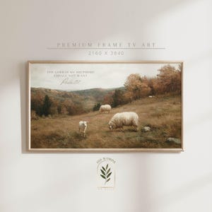 Op de afbeelding: Een ingelijste landschapsprint met schapen die grazen in een veld. Het kunstwerk heeft een warm kleurenpalet en de tekst "THE LORD IS MY SHEPHERD I SHALL NOT WANT Psalm 23:1". De lijst is van licht hout.