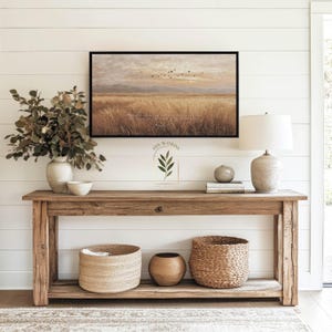 May include: A rustic wooden console table with a framed landscape painting, a lamp, and decorative baskets. The painting depicts a field with birds in flight. The text "HIS WORDS" is visible on the wall.