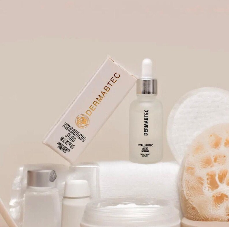 May include: A skincare product set featuring a bottle of hyaluronic acid serum and its packaging. The serum bottle is frosted glass with a dropper, and the box is white with gold lettering. Other skincare items are also visible.