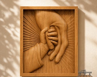 May include: A rectangular wooden wall art piece featuring a relief carving of a large hand holding a smaller hand. The design includes a sunburst pattern in the background and is enclosed in a simple wooden frame. The text CNC ROUTER IDEAS is visible.