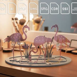 May include: A pink flamingo-shaped jewelry holder with three flamingos, holding earrings and necklaces. The holder is on a gray oval base with a digital file icon set in the background.
