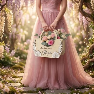 May include: A person in a pink dress holds a wooden basket filled with pink and white roses. The basket has the words "Love You Forever Mom" engraved on it. The background is a garden with purple flowers.