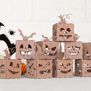 Puede incluir: Un conjunto de decoraciones de Halloween de madera marrón cortadas con láser. El conjunto incluye cajas de calabaza con caras talladas, murciélagos, arañas y una calabaza. Una caja dice "Happy Halloween" y otra "Trick or Treat".