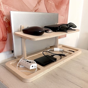 May include: A wooden laptop stand with a shelf for a mouse, sunglasses, and other small items. The stand has a built-in cable management system and a lower shelf for a hard drive and other electronics.