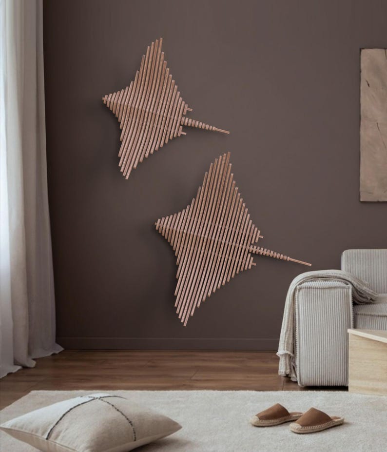 May include: Two wooden wall sculptures in the shape of stingrays, one larger than the other, mounted on a brown wall. The sculptures are made of thin strips of wood arranged in a geometric pattern.