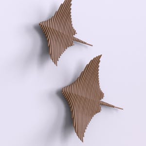 May include: Two brown wooden wall sculptures in the shape of stingrays. The sculptures are made of thin strips of wood that are layered and curved to create a 3D effect.