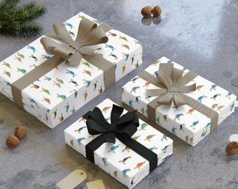 May include: Three gift boxes wrapped in white paper with a colorful turtle pattern. Each box is tied with a ribbon. Two boxes have taupe ribbons, and one has a black ribbon. The boxes are on a gray surface.