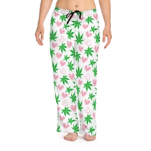 Puede incluir: Pantalón de pijama blanco con un patrón de hojas de marihuana verdes y corazones rosas.
