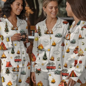 以下が含まれることがあります： キャンプをテーマにした白いパジャマセット。赤いテント、キャンプファイヤー、木、ヴィンテージカー、太陽の繰り返し模様が特徴です。長袖トップスとパンツは、柔らかくシルキーな素材で作られています。