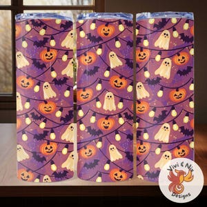 May include: Three Halloween-themed tumblers with a repeating pattern of orange jack-o'-lanterns, white ghosts, and black bats on a purple background. The design includes string lights. The tumblers are cylindrical and have a lid.