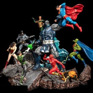 Può includere: Un gruppo di action figure che rappresentano i supereroi della DC Comics, tra cui Superman, Batman, Wonder Woman, Lanterna Verde, Flash e Aquaman, che combattono contro una grande figura di cattivo blu. Le figure sono in posa in una scena d'azione dinamica, con gli eroi che attaccano il cattivo.