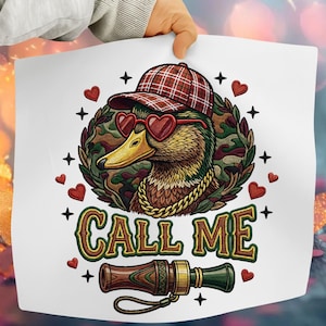 Peut inclure: Impression blanche avec un canard portant des lunettes de soleil en forme de cœur, une casquette à carreaux et une chaîne dorée. Le canard est entouré d'un motif camouflage, de cœurs et d'étoiles. Le texte "CALL ME" et un appeau sont également présents.