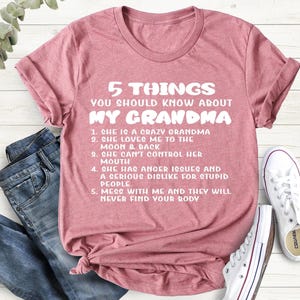 May include: A pink t-shirt with white text that reads "5 Things You Should Know About My Grandma". The text lists five humorous facts about grandmothers.