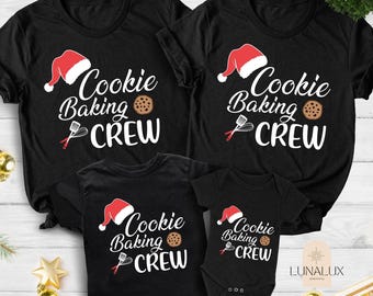 May include: Black t-shirts with the text "Cookie Baking Crew" in white script, a Santa hat, a cookie, and a whisk. The image shows four shirts of different sizes, including a baby onesie, perfect for a family.