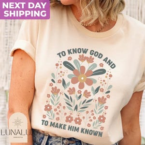 May include: Cream-colored t-shirt featuring a floral design with the text "TO KNOW GOD AND TO MAKE HIM KNOWN." The design includes flowers in shades of pink, green, and brown. The shirt also has the text "LUNALU SHINE IN STYLE" and "NEXT DAY SHIPPING."