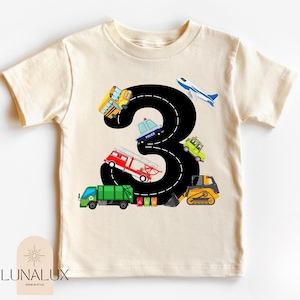 A t-shirt with a graphic design featuring a large number 3 surrounded by various vehicles, including a fire truck, police car, and construction equipment.