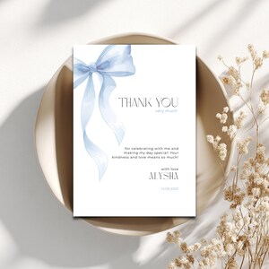 May include: A white card featuring a light blue watercolour bow and the words "THANK YOU" in elegant typography. The card includes the text "very much" and a personalized message, along with the name "ALYSHA" and the date 14.09.2025.