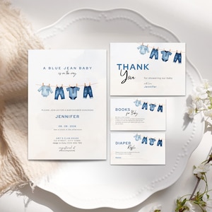 May include: A baby shower invitation set with a watercolor theme. The invitation and accompanying cards feature blue jean baby clothes hanging on a clothesline. The text includes the phrase "A Blue Jean Baby is on the way."