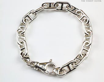 Könnte beinhalten: Ein poliertes Silberarmband mit einer Reihe ineinandergreifender Glieder im Mariner-Stil und einem zentralen Karabinerverschluss. Der Text ARGENTIUM THE FINEST SILVER und ein Einhorn-Logo stehen oben, SILVER BRACELET steht unten.
