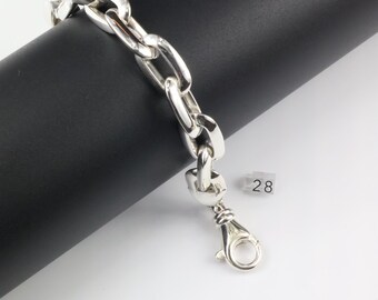 May include: A polished silver chain bracelet featuring thick, rounded oval links and a secure lobster claw clasp. A small, square white tag with the number 28 printed in black is attached to the bracelet near the clasp mechanism.