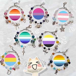 Può includere: Una collezione di braccialetti di perline con disegni di bandiere del pride. Ogni braccialetto ha una bandiera diversa, tra cui bandiere lesbiche, bisessuali, transgender, gay, non binari e pansessuali. I braccialetti hanno ciondoli e perline colorate.